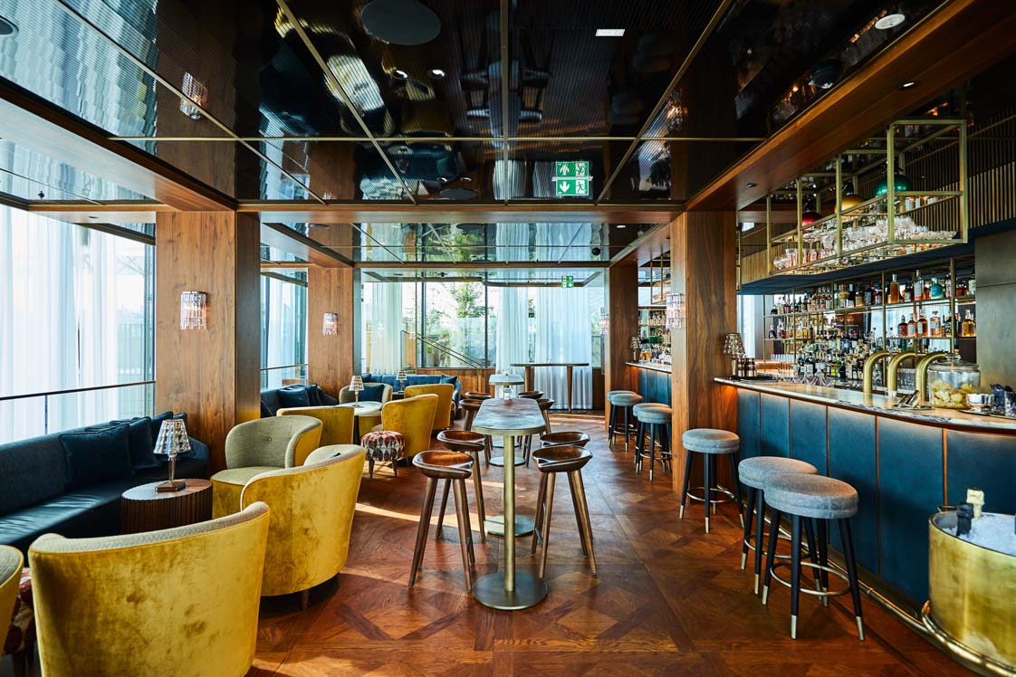 Rooftop-Jewels&nbsp;Die stilvolle Bar (BIld), das Restaurant und die Brasserie wurden von der Wiener Interieur-Schmiede Kroenland entworfen. Die Samtbezüge und der Holzboden vermitteln gemütliches Ambiente mit modernem Twist. kroenland.com