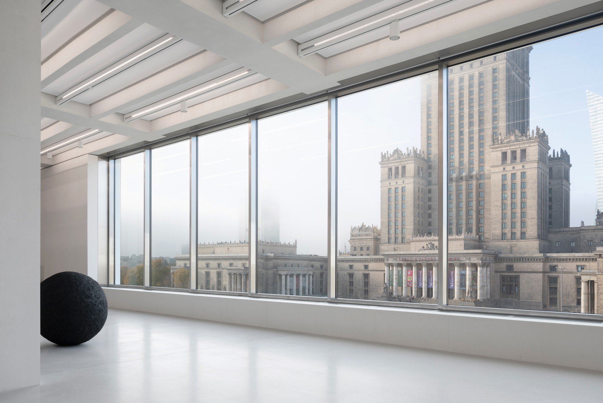 Harter Kontrast. Durch die Fensterfront des 
Museums für moderne Kunst blickt man auf den mächtigen Turm des stalinistischen Kultur­palasts aus den 1950er-Jahren.