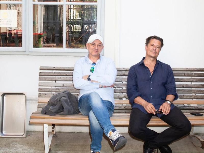 Zwei, die einander mögen. Josef E. Köpplinger und Michael Dangl haben vielfältige berufliche Berührungspunkte und ziehen künstlerisch an einem Strang. Das Interview gaben sie nach der Probe auf einer Sitzbank hinter der Piaristenkirche Maria Treu.