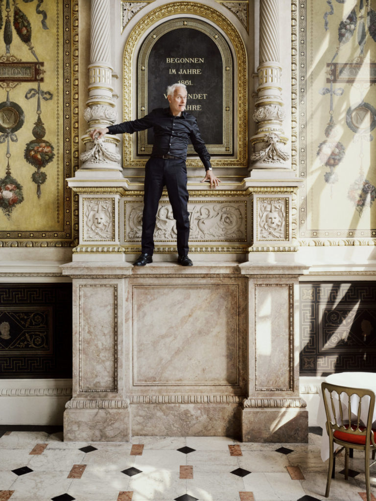 Herbert Fritsch in fast zwei Meter Höhe auf einem Sims der Loggia des Schwindfoyers in der Staatsoper. Wie er da raufgekommen ist, ist unser Geheimnis. Jedenfalls ohne Leiter …