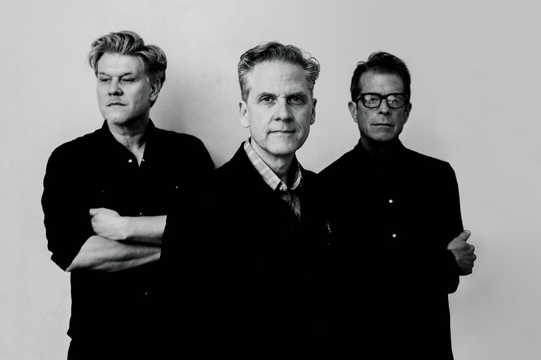 Calexico sind eine US-amerikanische Indie-Rock-Band aus Tuscon, Arizona, die 1996 von Joey Burns und John Convertino gegründet wurde. Benannt sind sie nach der kalifornischen Grenzstadt Calexico. Ihren Durchbruch hatte die Band mit dem 2003 erschienenen Album „Feast of Wire“. In Wien sind John Convertino, Joey Burns und Martin Wenk (von rechts) zum ersten Mal Teil einer Theaterproduktion. Für den Abend schreiben sie neue Songs. Auch Paul Wallfisch, Musikchef des Volkstheaters, spielt eine zentrale Rolle in der Inszenierung.