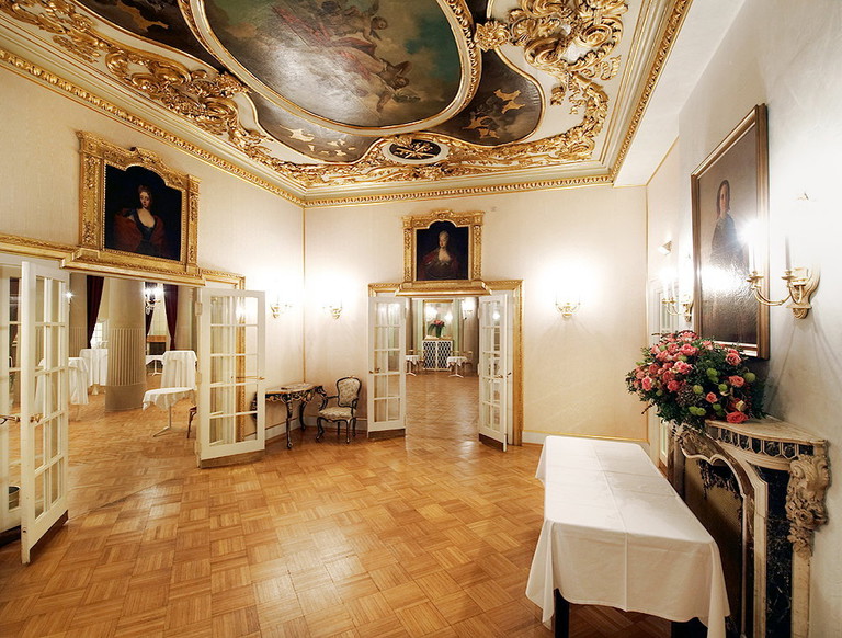 Der gelbe Salon besticht durch seine mit vergoldeten Ornamenten reich verzierte Decke und drei außergewöhnliche Damenporträts.