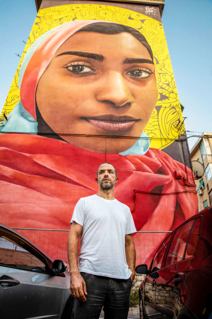 Die Heilige und der Dirigent. Omer Meir Wellber im Kalsa-Viertel in Palermo, einem Mekka der Graffiti-Kunst. Die – meist anonymen – Künstler*innen arbeiten im Auftrag der Stadt. Dieses Werk zeigt eine Sklavin, die in Südafrika heiliggesprochen wurde. 