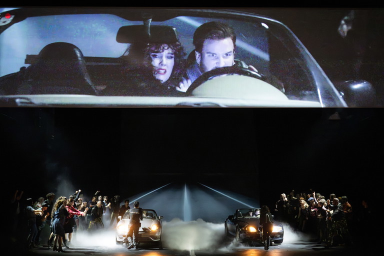 Ständig filmen zwei Live-Kameras das Geschehen und machen jedes emotionale Detail sichtbar. Auf der Leinwand vergrößert: Mélissa Petit (Juliette) und Andrew Hamilton (Paris). Auf der Bühne: Mélissa Petit, Andrew Hamilton, Arnold Schoenberg Chor und das Ensemble.
