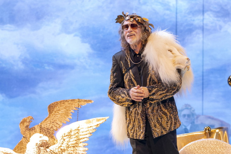 Lassen Sie dieses Bild wirken. Wenn Sie John Malkovich (unter anderem) auf einem goldenen Flügelwagen sehen wollen – dann sollten Sie in die Wiener Staatsoper gehen.