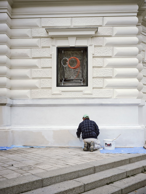 Ein Arbeiter verspachtelt die letzten Flächen an der Fassade. Dort, wo Sie jetzt noch Kabel sehen, werden bald die neuen Schau­kästen montiert.