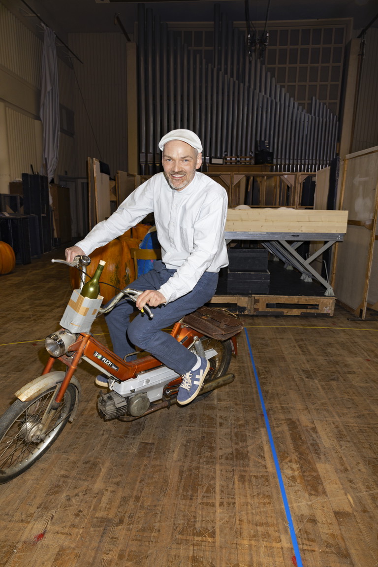 Einmal Vollgas ohne Gas. Das Moped ist eine Legende. Regisseur Dirk Schmeding auf der alten Puch, die auch fährt, wenn man nur tritt. Sie wird Teil der Inszenierung – „eines Dorfes, das irgendwo zwischen den Zeiten hängengeblieben ist, abgeschnitten von den Trends“.