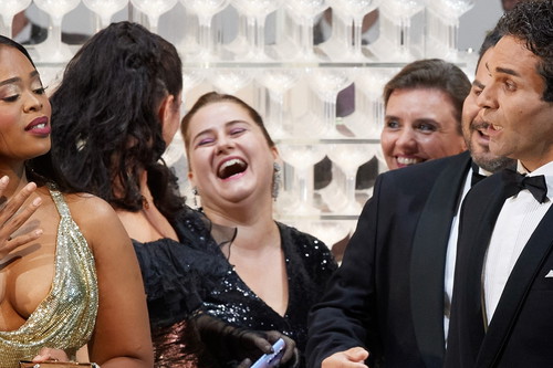 Mehrere elegant gekleidete Personen stehen zusammen und lachen herzlich bei einem festlichen Anlass.